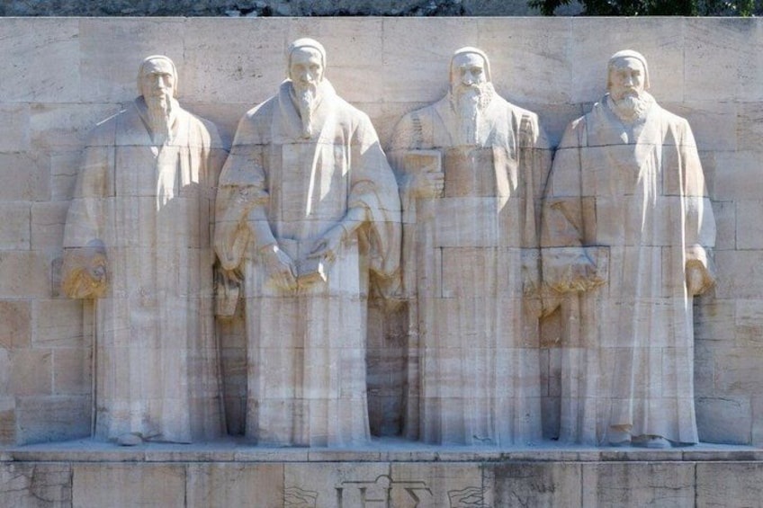 A stone monument with four statues of robed figures. 3