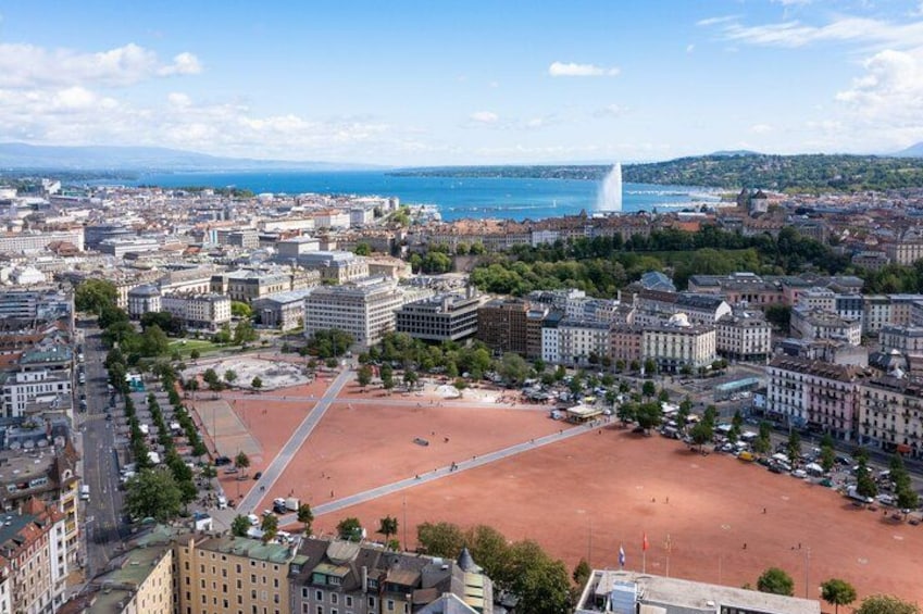 A cityscape with a large open square, buildings, and a body of water in the background. 4