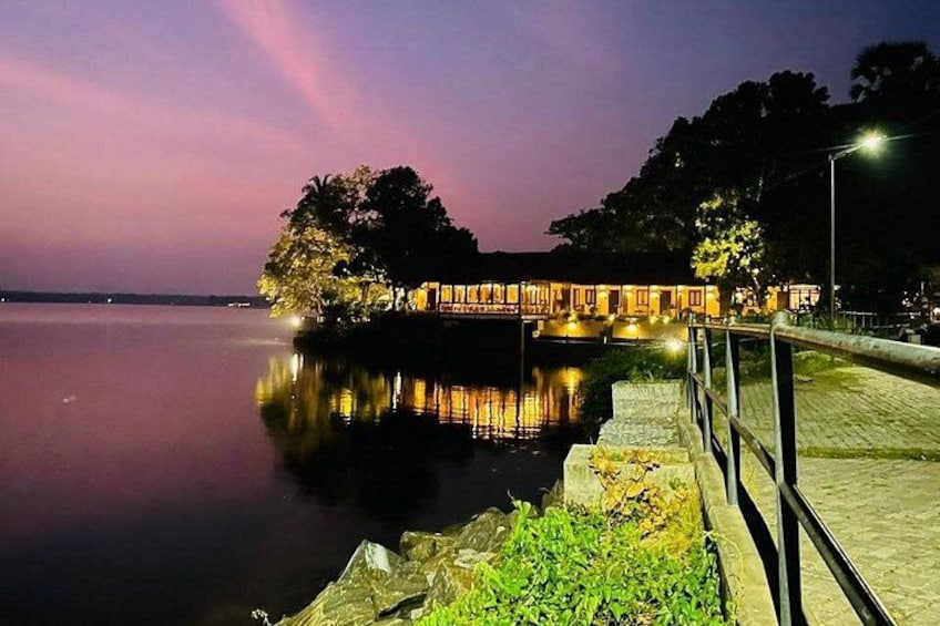 A calm lake at dusk with a dock and buildings illuminated by warm lights. 3