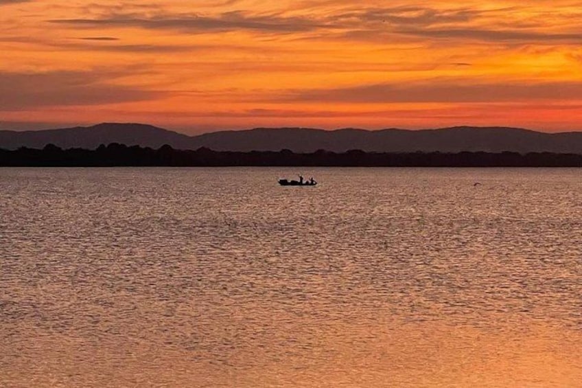 A sunset over a calm body of water with a silhouette of mountains in the background. 4