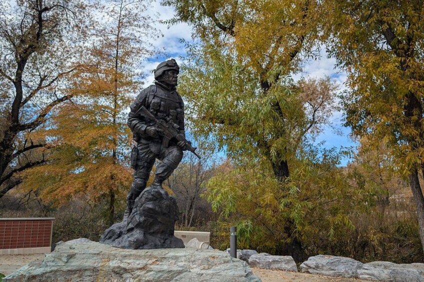 A statue of a soldier on a rock in a park with autumn trees. 3