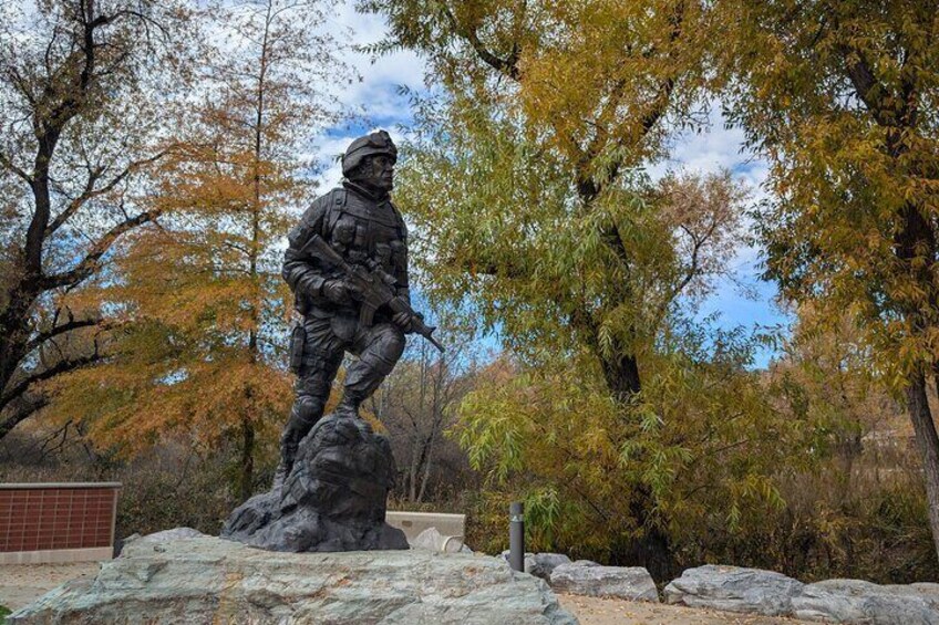 A statue of a soldier in a forested area with autumn-colored trees. 2