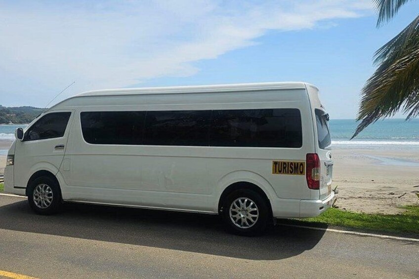 Een witte bestelwagen staat op een weg in de buurt van een strand, met een heldere lucht. 5