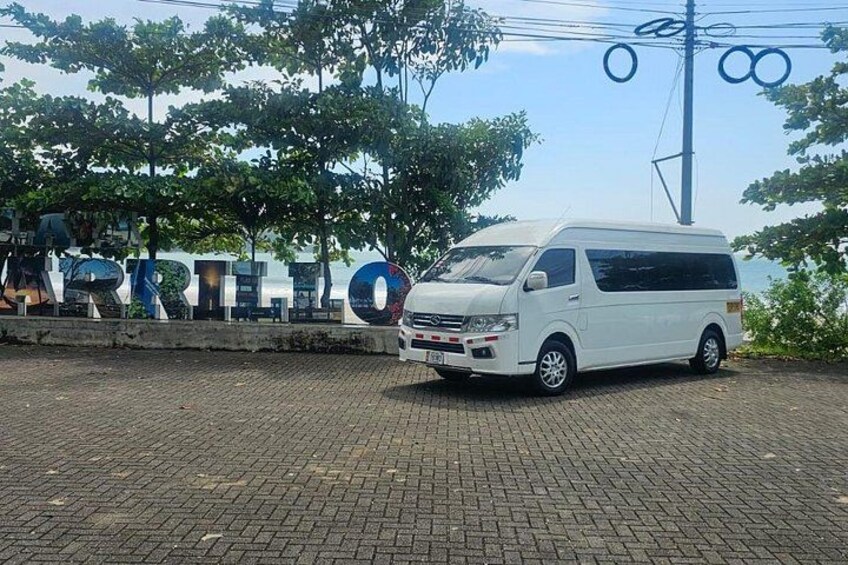 Een witte bus geparkeerd voor een bord met de tekst 'ARRILLO'. 4