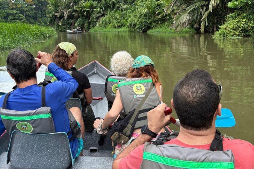 En gruppe mennesker i en båd på en flod omgivet af grønt. 4