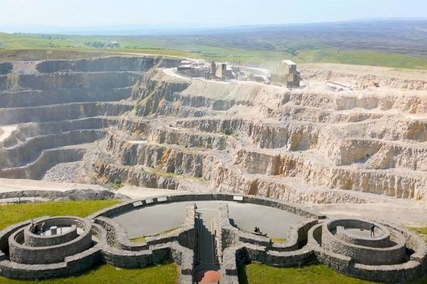 Una gran estructura de piedra circular con anillos concéntricos, rodeada de colinas escalonadas. 5