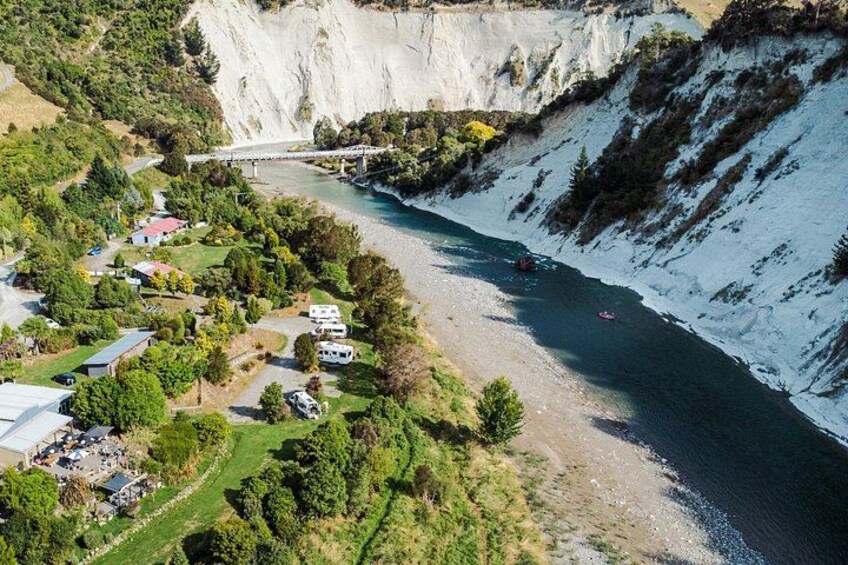 A river with a steep cliff, a bridge, and a small settlement with RVs. 3