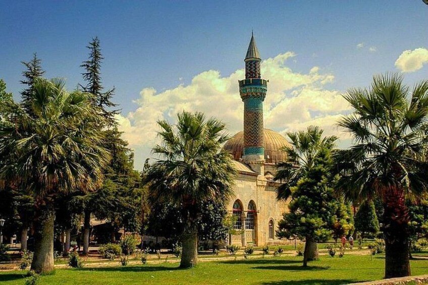 A mosque with a tall minaret, surrounded by palm trees and a well-maintained garden. 1