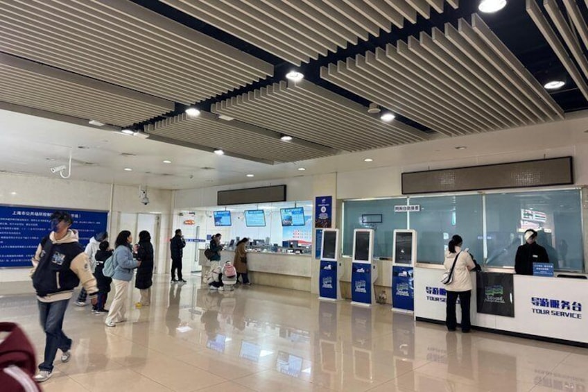 A modern indoor space with a check-in counter, digital information screens, and a polished floor. 5