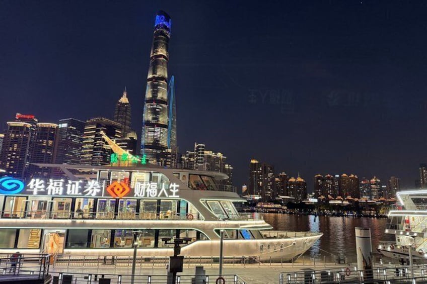 A nighttime cityscape with a prominent skyscraper, a river, and a boat docked at a pier. 2