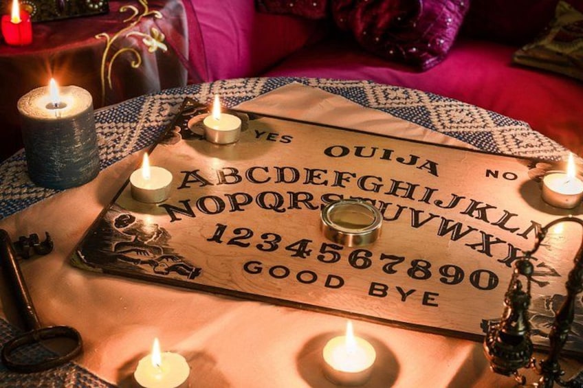 A Ouija board with candles and a crystal ball on a table. 2