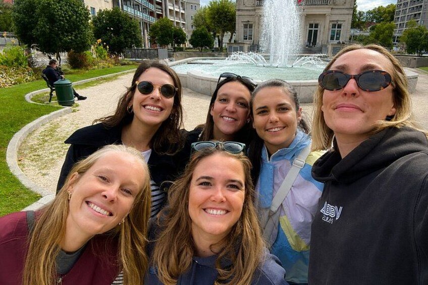 Un grupo de personas posando frente a una fuente con edificios al fondo. 1