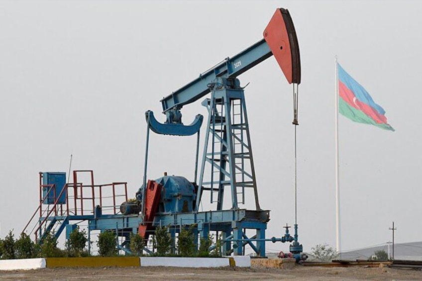 An oil pumpjack with a flag in the background. 1