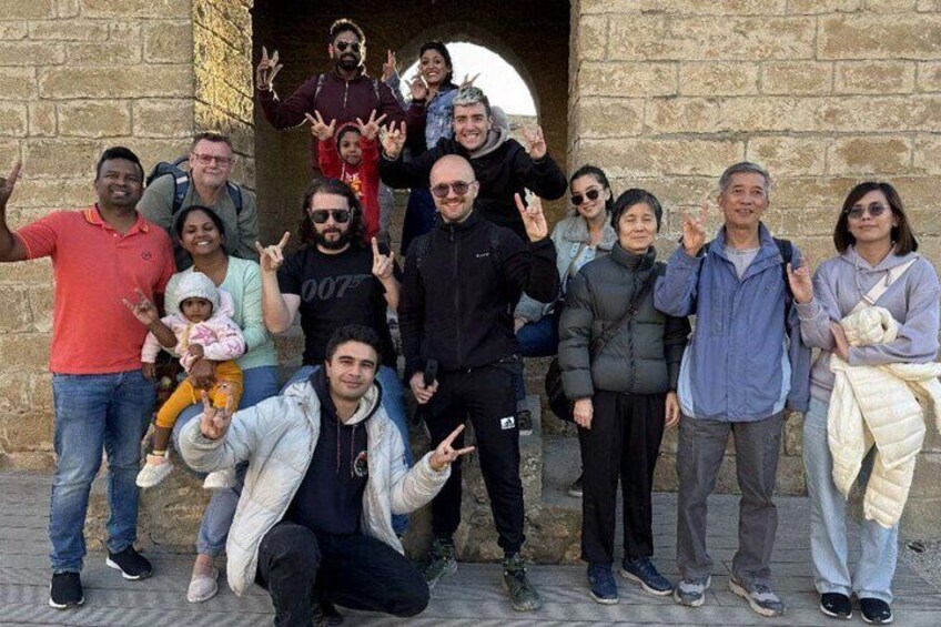 Un grupo de personas posando frente a un edificio de piedra con una entrada arqueada. 3