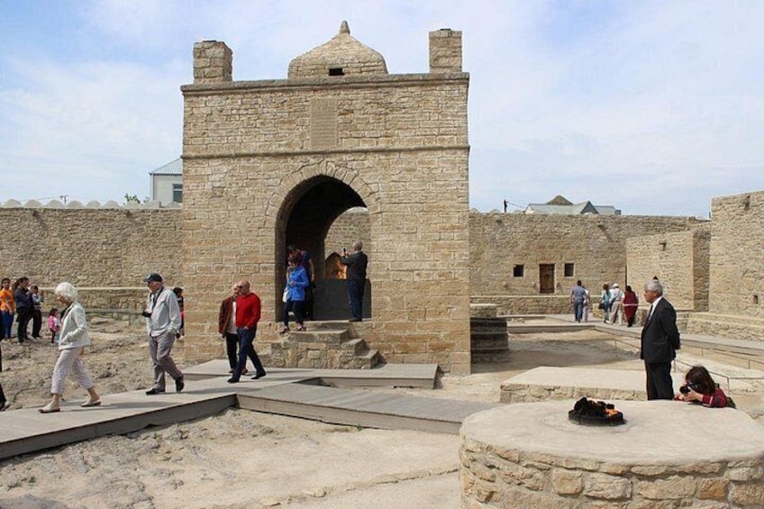 Antigua estructura de piedra con una entrada arqueada, rodeada de visitantes. 2