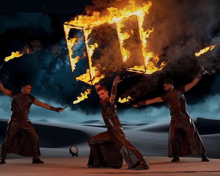 Three individuals performing a fire act with a large fire structure. 4