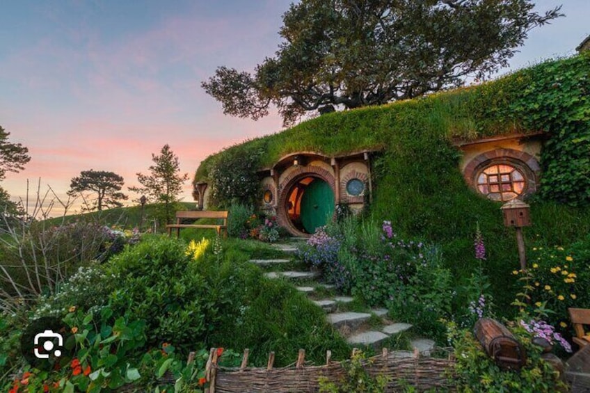 Hus i hobbitstil med gröna tak, en trädgårdstig och en bänk. 5