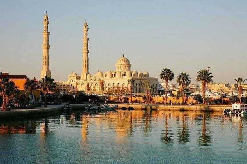 A mosque with two minarets and a large dome, reflecting in calm water. 1