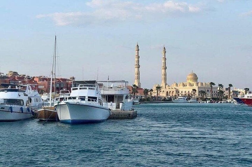 A marina with several boats, a mosque with two minarets, and a dome in the background. 5