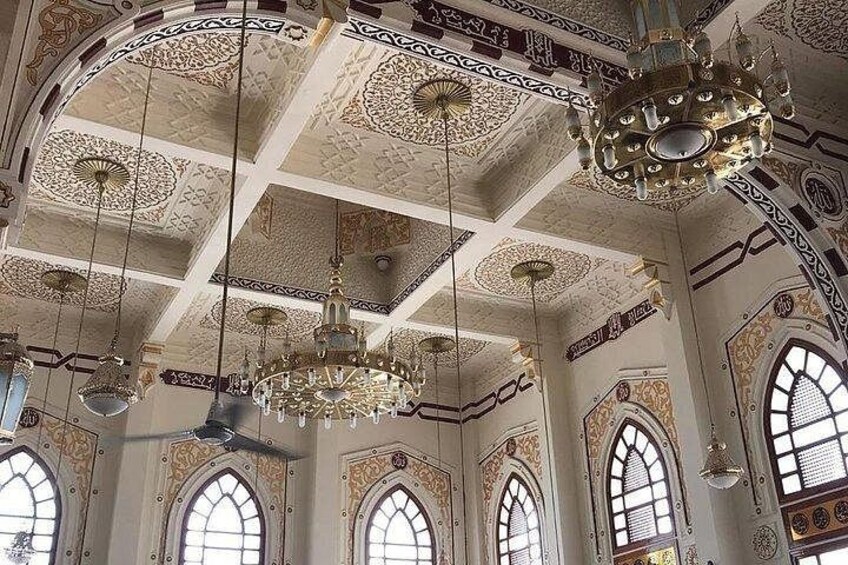 An ornate interior with intricate ceiling designs, chandeliers, and arched windows. 2