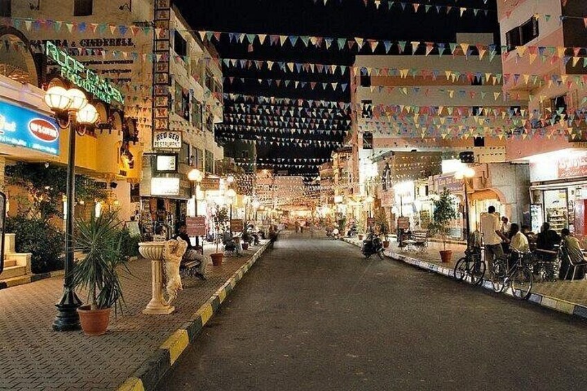 A nighttime street with shops, potted plants, and bicycles. 3