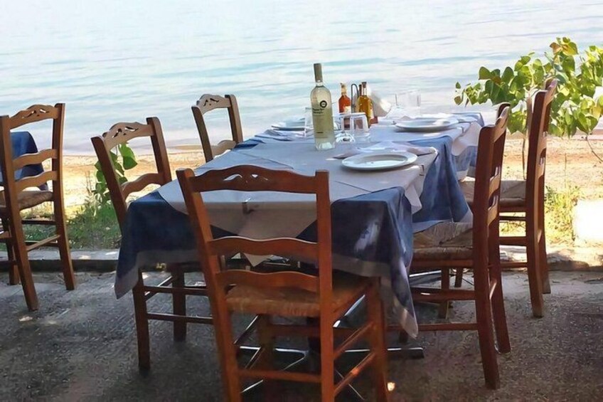 A table set for dining with chairs, a tablecloth, and bottles of water and olive oil. 2