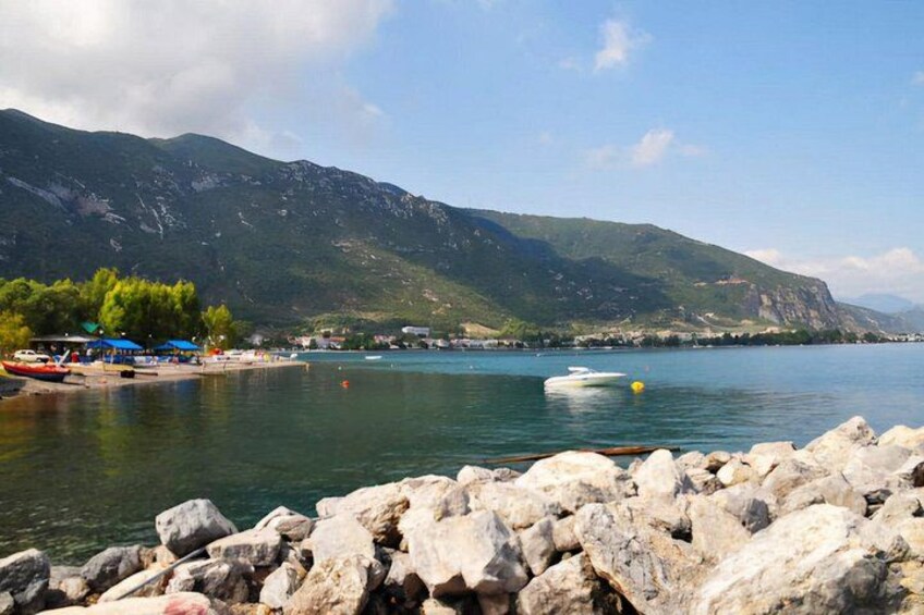 A lake with boats, a rocky shore, and mountains in the background. 3