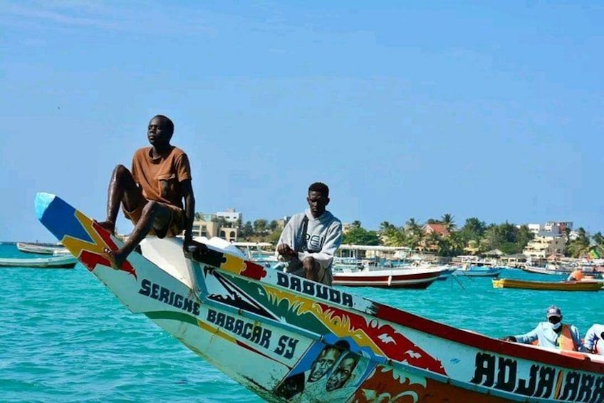 A person sitting on a colorful boat with a tropical background. 2