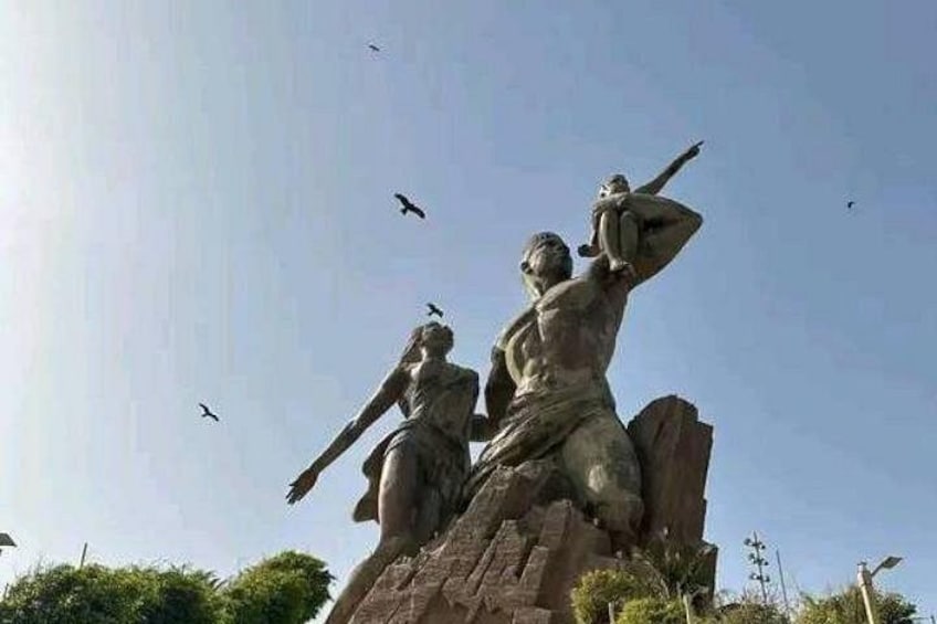 A statue of two figures, one standing and one kneeling, with birds flying around. 1