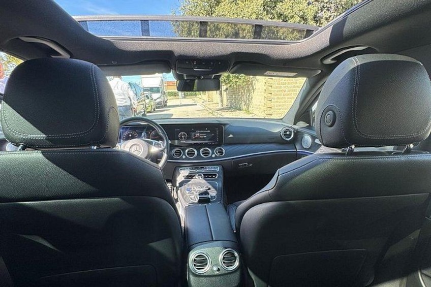 The interior of a car with leather seats, a central console with buttons and dials, and a sunroof. 5
