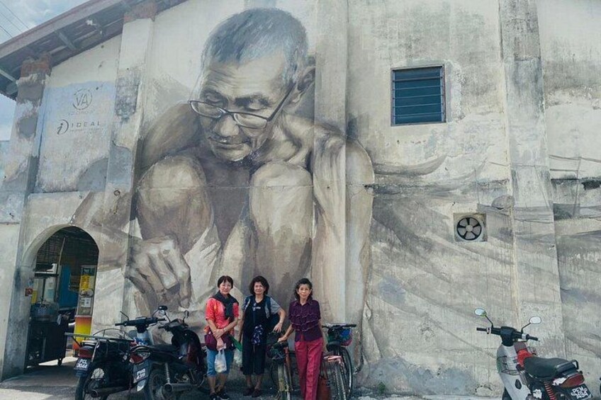 A mural of a muscular figure on a building, a group of people, and parked motorcycles. 1