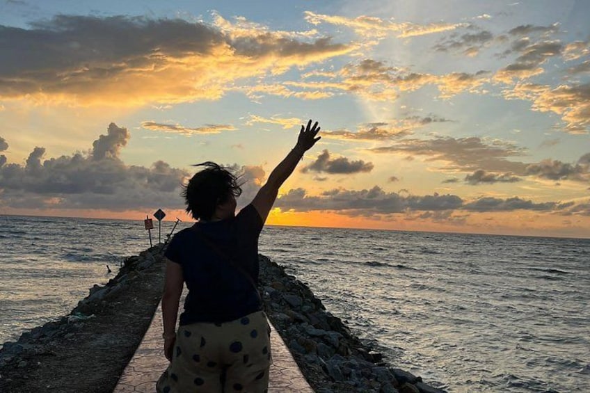 A person walking on a rocky path by the sea during sunset. 2