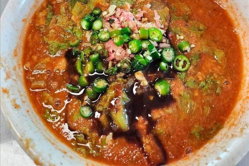 A bowl of soup with green peppers and a red sauce. 4