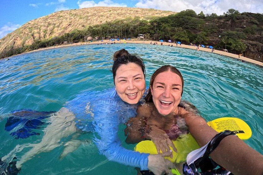 Two people in a swimming pool with a beach and hills in the background. 5
