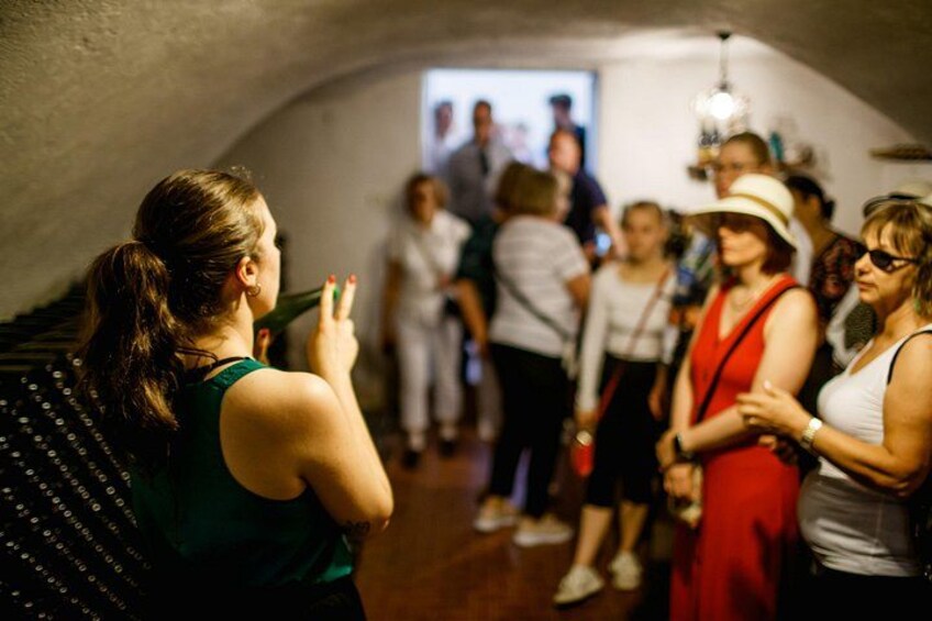 Un gruppo di persone in una stanza a volta scarsamente illuminata, con uno schermo proiettore sullo sfondo. 4