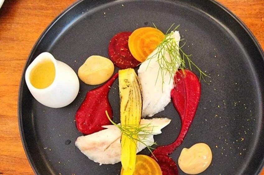 Un plato con diferentes alimentos como pescado, remolachas y hierbas. 2