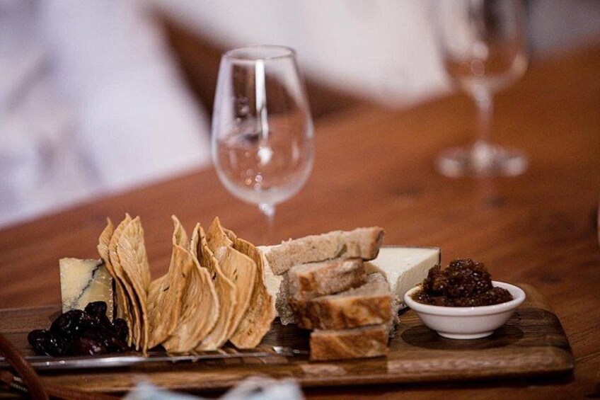 Una tabla de madera con queso, galletas y un bol de caviar sobre una mesa. 3