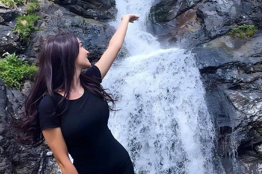 A person standing in front of a waterfall with water cascading down rocks. 4