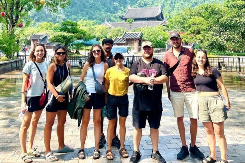 A group of people standing in a park with a traditional building in the background. 3