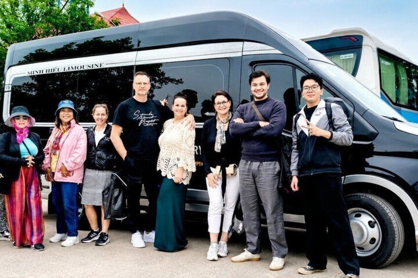 A group of people standing in front of a vehicle with 'MINH HIEU LIMOUSE' written on it. 2
