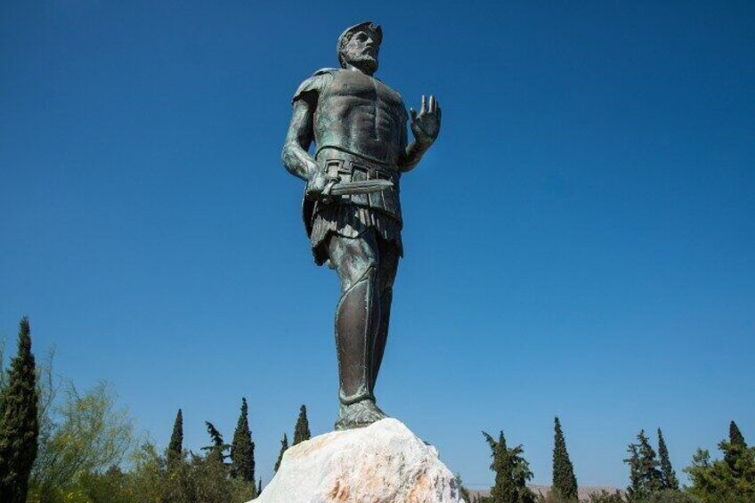 A bronze statue of a historical figure on a pedestal, surrounded by trees and a clear sky. 2
