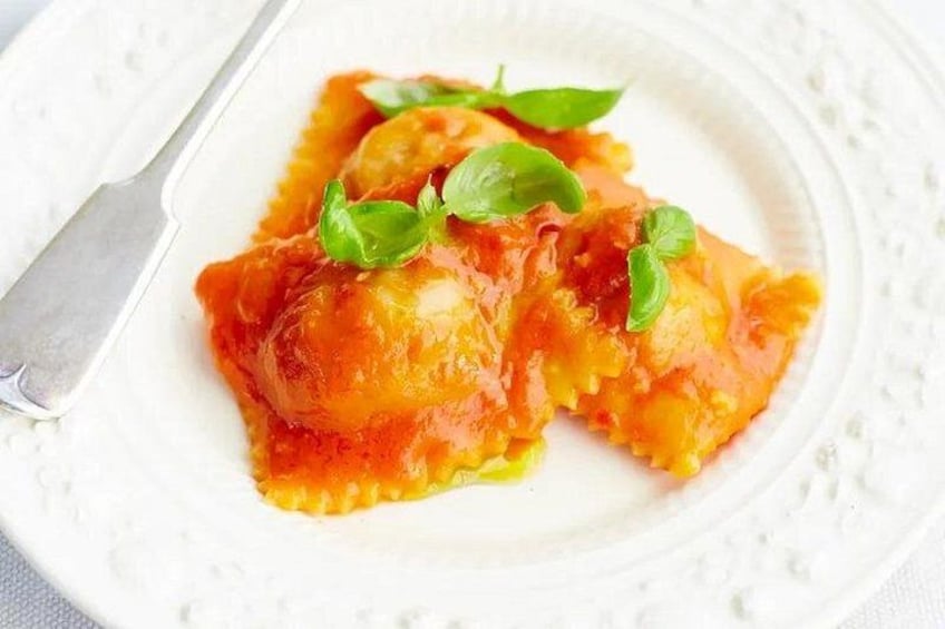 Ravioli with tomato sauce and basil garnish on a white plate. 4