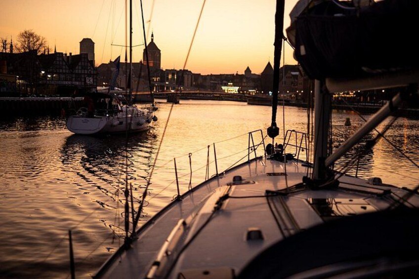 Een boot ligt aangemeerd in een haven, met gebouwen op de achtergrond tijdens de zonsondergang. 4