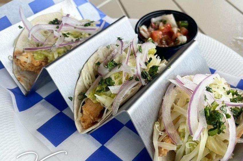 Three tacos with toppings on a paper plate. 3