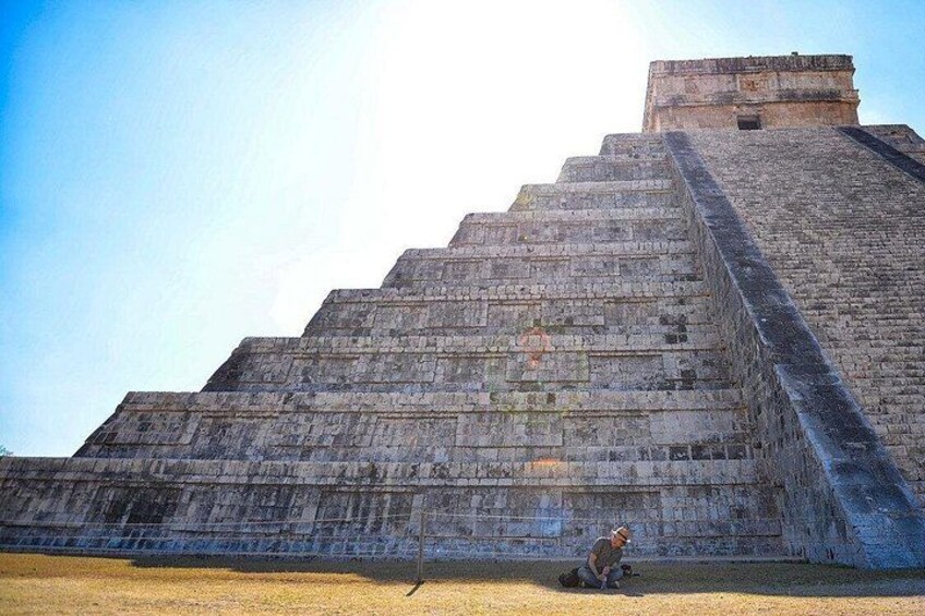 A large stone pyramid with a person sitting at its base. 1