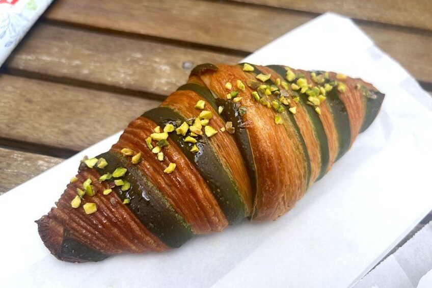 Un croissant con glaseado brillante y pistachos picados sobre una servilleta blanca. 2