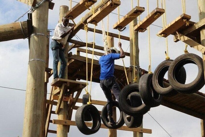Two people climbing a wooden structure with tires as steps. 3
