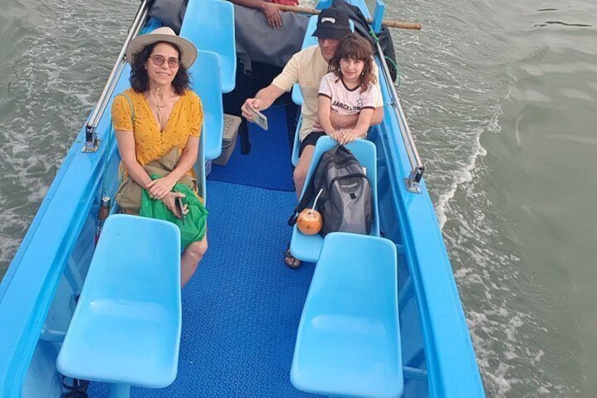 A small blue boat with two passengers and a child, moving on calm water. 4