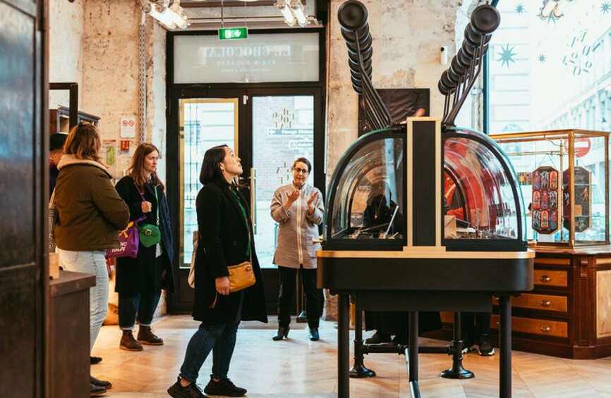 A group of people inside a building with a glass display case and a sign above the entrance. 2