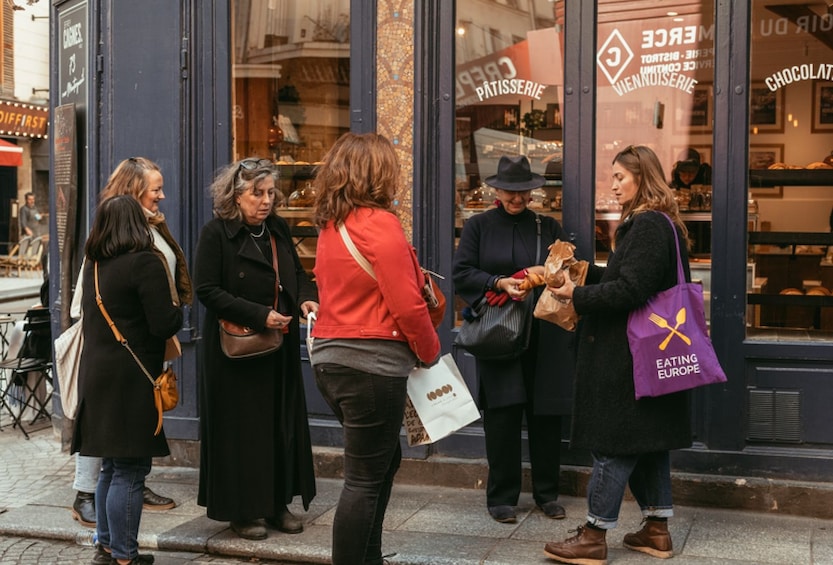 A group of people standing outside a bakery with a sign that reads 'CHOCOLAT'. 3